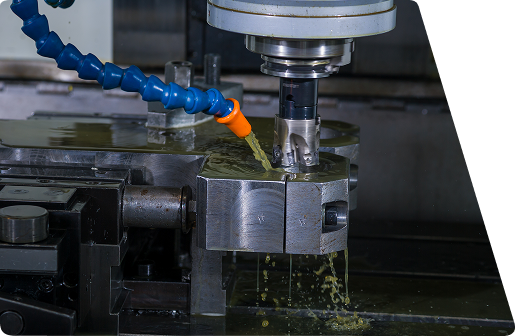 CNC milling machine cutting a metal workpiece with coolant being applied from a blue nozzle.