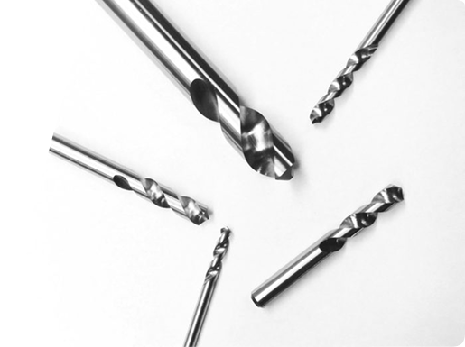 Five metallic twist drill bits of varying sizes arranged on a plain white background.
