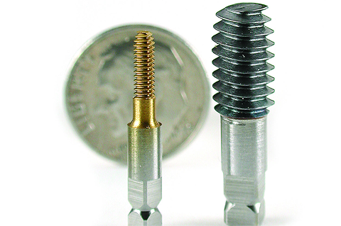 Small and large metal threading taps standing vertically in front of a US dime.