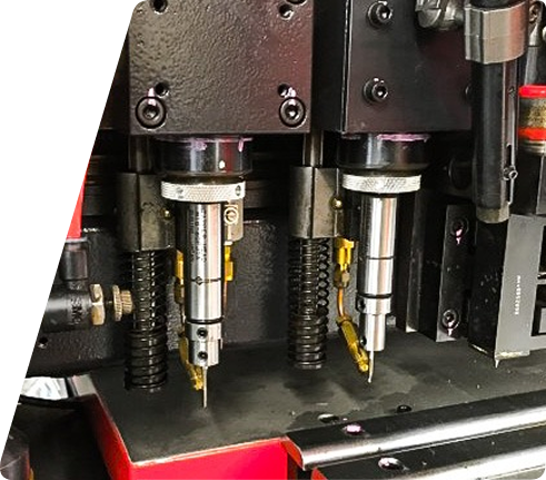 Close-up of industrial machinery featuring two vertical drilling spindles with metal components and mechanical connections.
